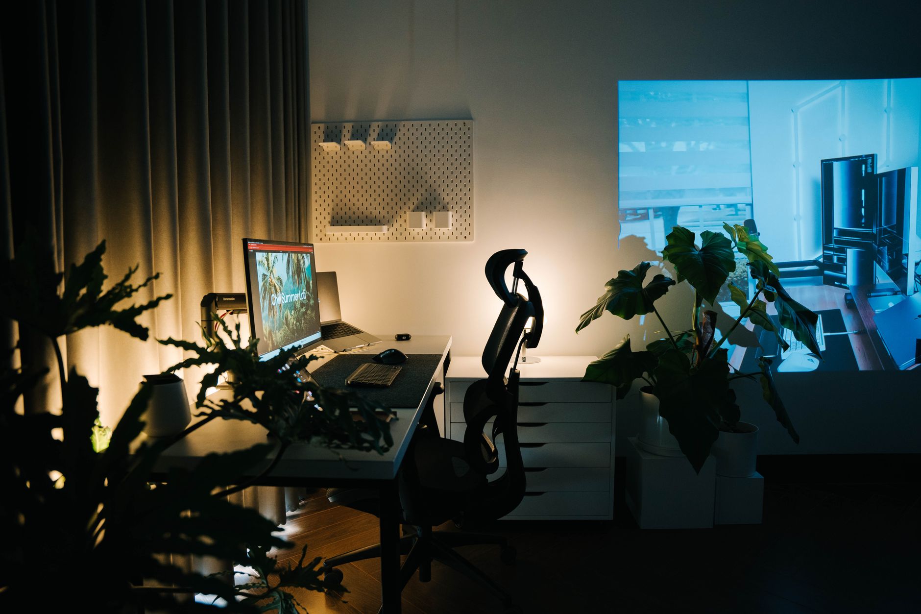 Scrivania di un ufficio domestico con luce ambientale e piante, allestita per il lavoro da casa
