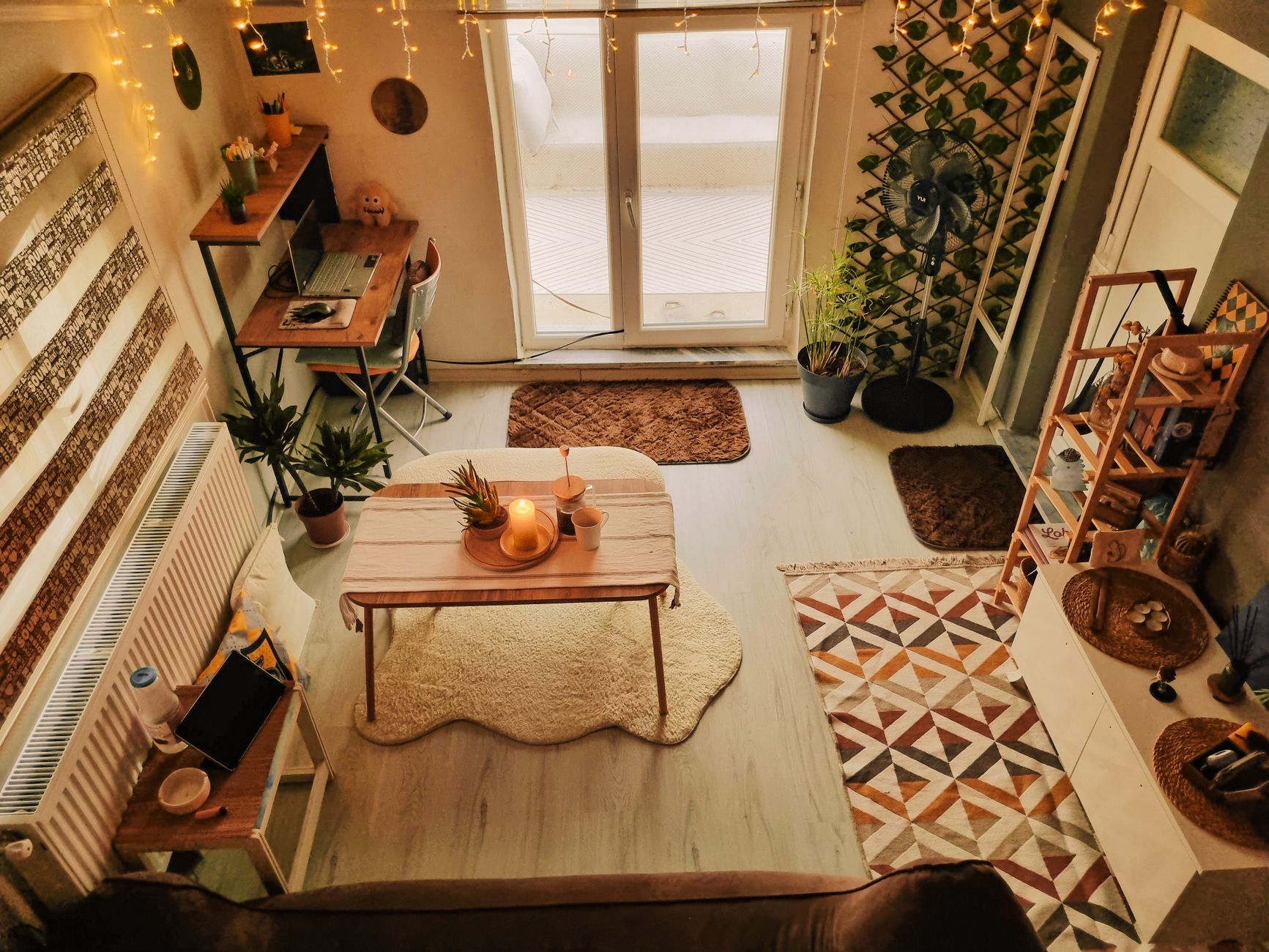 Soggiorno accogliente con scrivania in legno, piante e luci decorative